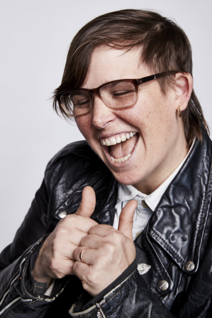 Picture of a gender-neutral person wearing a leather jacket giving two thumbs up.