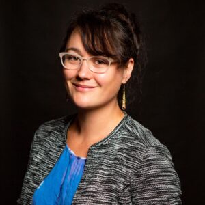 Image of a smiling multiracial woman with black hair in front of a black background
