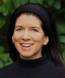 Smiling white woman with dark hair in front of green background