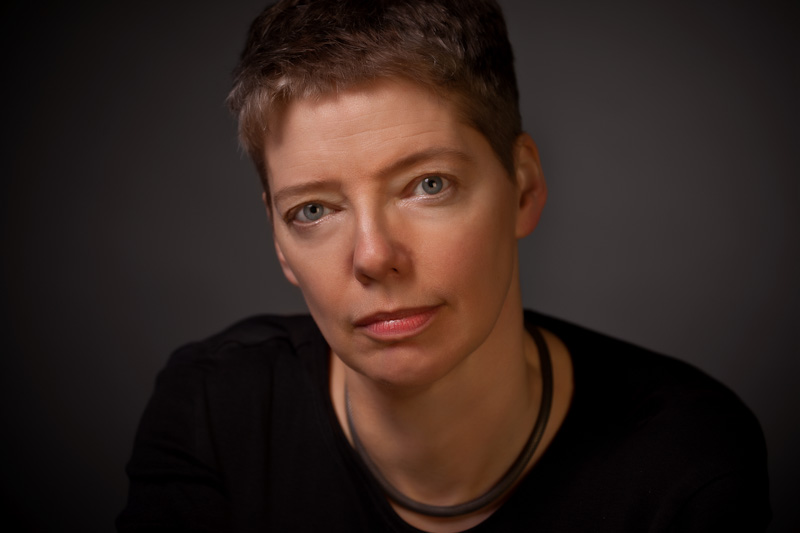 A white woman with short hair wearing a dark shirt looks forward. Nicola Griffith.